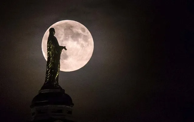 The Supemoon silhouettes the statue of the Virgin Mary on top of the University of Notre Dame's golden dome in South Bend, Indiana. (Photo by Robert Franklin/South Bend Tribune)