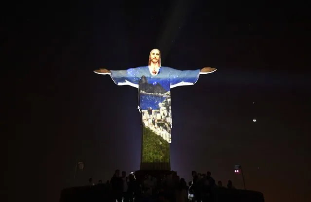 The Christ is lit with special Led lights by French artist Gaspare Di Caro on the Corcovado hill on August, 5 2016 in Rio de Janeiro a few minutes before the Opening ceremony of the Rio 2016 Olympic Games. The carnival capital of the world is hoping Friday's extravaganza at the Maracana Stadium will draw a line under a turbulent seven-year build-up dogged by recession, rising crime and doping scandals. (Photo by Jeff Pachoud/AFP Photo)