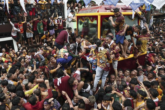Devotees climb on a glass-covered carriage carrying the image of Jesus Nazareno during its annual procession in Manila, Philippines, Thursday, January 9, 2025. (Photo byh Basilio Sepe/AP Photo)