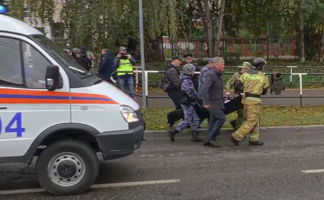 In this image taken from video, servicemen and emergency employees carry the wounded from the scene of a shooting at school No. 88 in Izhevsk, Russia, Monday, September 26, 2022. (Photo by Izhlife.ru via AP Photo)