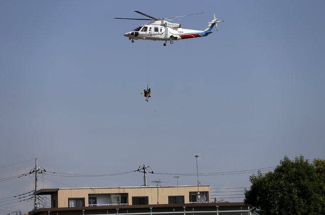 A firefighter's helicopter from Yamanashi Prefecture hoists a local resident rescued at a residential area flooded by the Kinugawa river, caused by typhoon Etau, at Mitsukaido district in Joso, Ibaraki prefecture, Japan, September 12, 2015. (Photo by Issei Kato/Reuters)