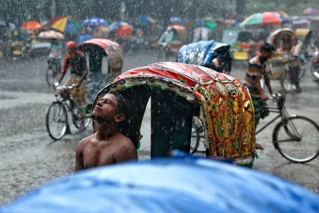 A rickshaw puller enjoys rain during monsoon in Dhaka, Bangladesh on September 8, 2022. (Photo by Mohammad Ponir Hossain/Reuters)
