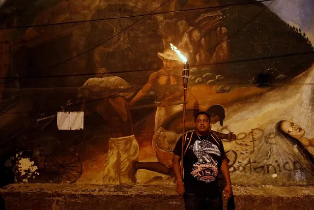 A demonstrator holds a torch as he stands in front of a mural during a march to demand the resignation of Honduras' President Juan Orlando Hernandez in Tegucigalpa, September 11, 2015. (Photo by Jorge Cabrera/Reuters)