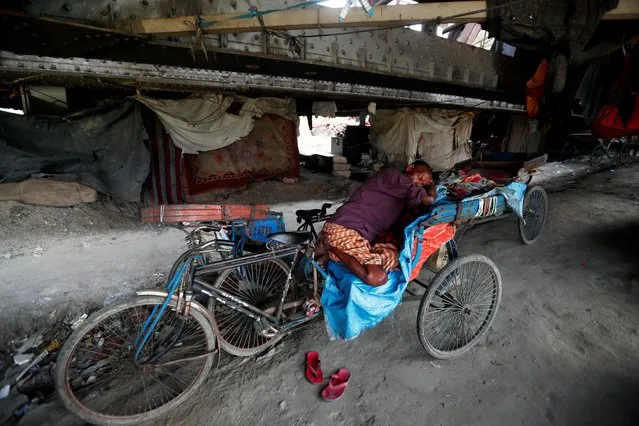 A man sleeps on a cycle rickshaw under a railway bridge on a hot summer day in New Delhi, India, May 27, 2020. (Photo by Adnan Abidi/Reuters)