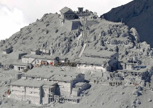 Japan Self-Defense Force (JSDF) soldiers and firefighters make rescue works among mountain lodges, covered with volcanic ash near the peak of Mt. Ontake, which straddles Nagano and Gifu prefectures in this September 28, 2014 photo taken and released by Kyodo. (Photo by Reuters/Kyodo News)