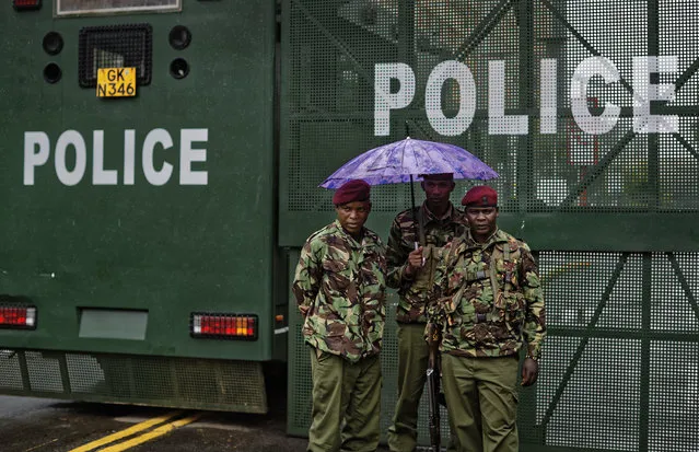 Kenyan police stand under the rain by a barrier blocking off vehicle and pedestrian access, amid tight security outside the Supreme Court in downtown Nairobi, Kenya Tuesday, November 14, 2017. The Supreme Court is due to hear petitions challenging President Uhuru Kenyatta's re-election in October's repeat presidential poll, after it previously had nullified Kenyatta's August reelection citing irregularities and illegalities. (Photo by Ben Curtis/AP Photo)