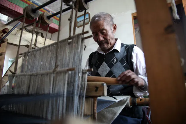 Dawa, a 68 year-old Tibetan, uses an embroidery loom to weave sheep cotton into 18-meter-long robes that make up the traditional outfit in Lhoka county (Shannan in Chinese) in the Tibet Autonomous Region in China, Saturday, September 19, 2015. (Photo by Aritz Parra/AP Photo)