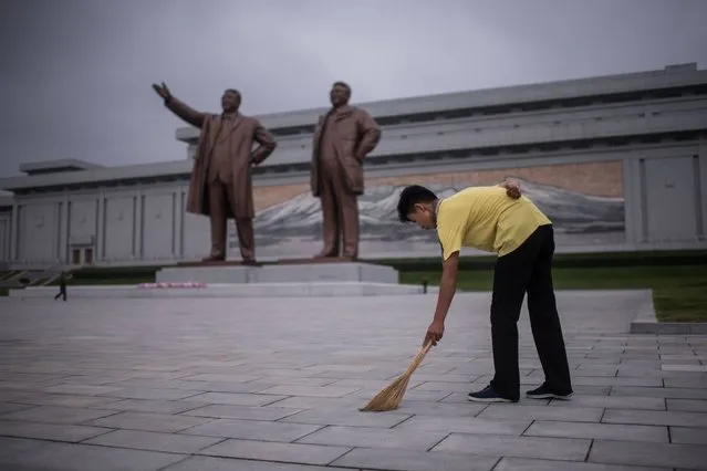 A Pyongyang resident undertakes volunteer work as he sweeps around the statues of former North Korean leaders Kim Il-Sung (L) and Kim Jong-Il (R), on Mansu hill in Pyongyang on July 13, 2016. (Photo by Ed Jones/AFP Photo)