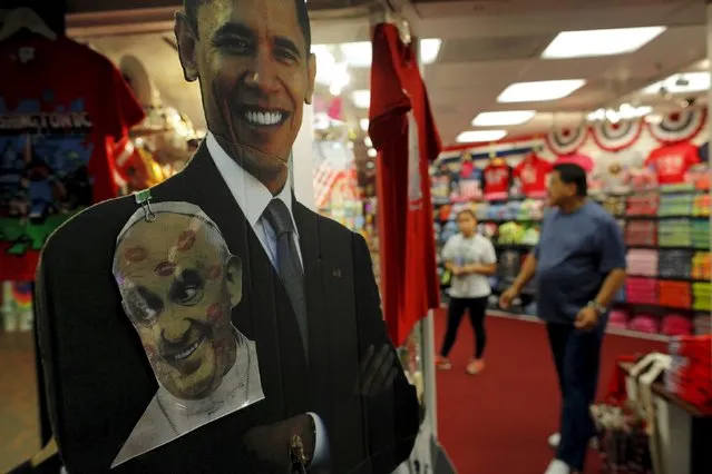 A picture of Pope Francis hangs on a cardboard cutout of U.S. President Barack Obama outside a souvenir shop in a subway station in Washington, DC September 22, 2015, ahead of the Pope's visit to the United States. (Photo by Brian Snyder/Reuters)