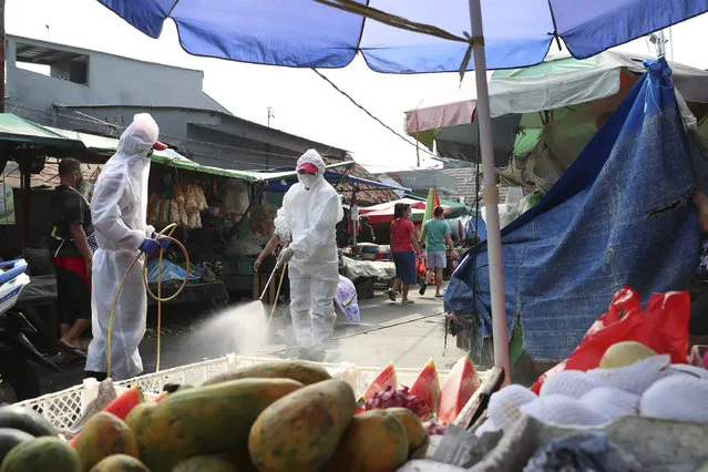 Members of Indonesia Red Cross spray disinfectant in an attempt to help curb the spread of the new coronavirus at a market in Jakarta, Indonesia, Wednesday, June 24, 2020. (Photo by Achmad Ibrahim/AP Photo)