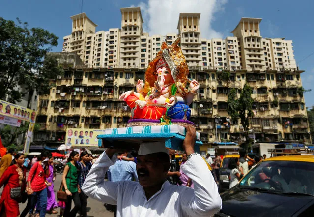 A devotee carries an idol of the Hindu god Ganesh, the deity of prosperity, to a place of worship on the first day of the Ganesh Chaturthi festival in Mumbai, India, September 5, 2016. (Photo by Danish Siddiqui/Reuters)