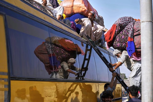 A laborer loads belongings of Afghan refugees onto the roof of a bus as the refugees prepare to return to Afghanistan, at a terminal in Karachi, Pakistan, Wednesday, April 9, 2025. (Photo by Fareed Khan/AP Photo)
