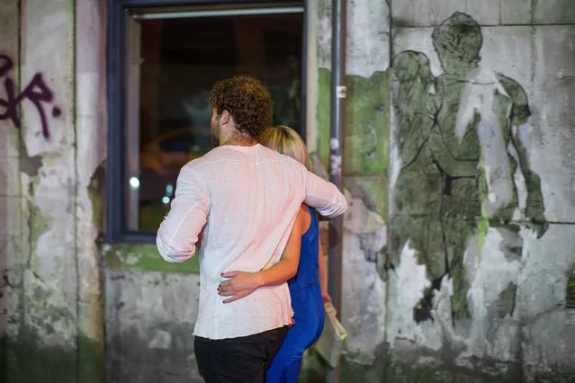 A couple walk arm in arm past pasted street art of a couple walking arm in arm on Dantzic Street in Manchester, UK on September 11, 2016. (Photo by Joel Goodman/London News Pictures)