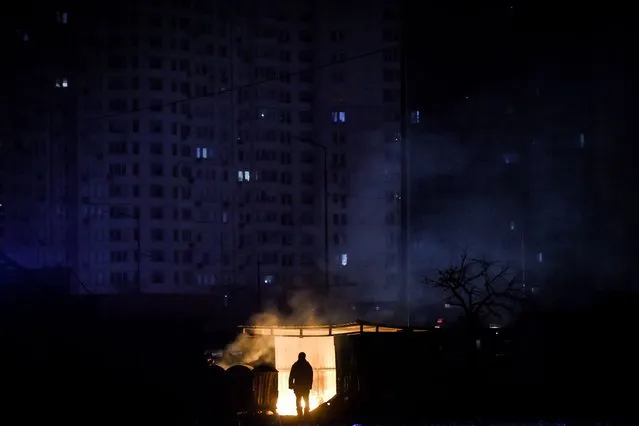 A man stands near burning garbage in front of an apartment building during a scheduled power cut in Kyiv (Kiev), Ukraine, 28 November 2022. According to a statement by Ukraine's national power supply Ukrenergo on 28 November, power cuts have been applied throughout Ukraine due to emergency shutdown of units at several power plants as a result of waves of Russian missile attacks on the energy infrastructure. Energy consumption has grown in the country due to worsening weather conditions, with scheduled power cuts being a temporary solution to prevent emergency situations in the networks. Russian troops on 24 February entered Ukrainian territory, starting a conflict that has provoked destruction and a humanitarian crisis. (Photo by Oleg Petrasyuk/EPA/EFE)