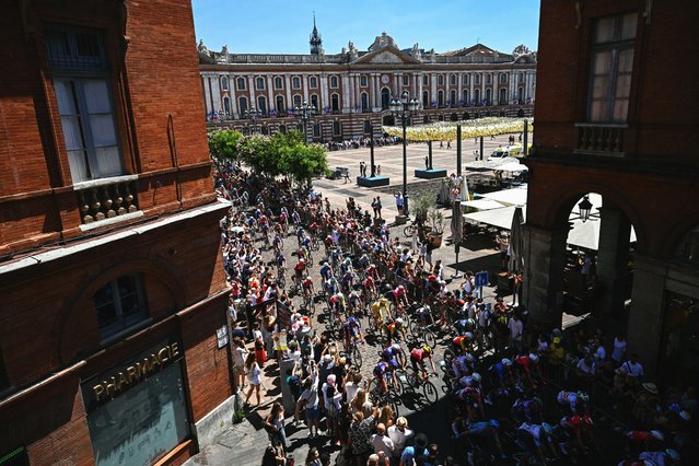 The pack of riders (peloton) cycles past the Place du Capitole in central Toulouse during the 11th stage of the 112th edition of the Tour de France cycling race, 156.8 km starting and finishing in Toulouse, southwestern France, on July 16, 2025. (Photo by Loïc Venance/AFP Photo)
