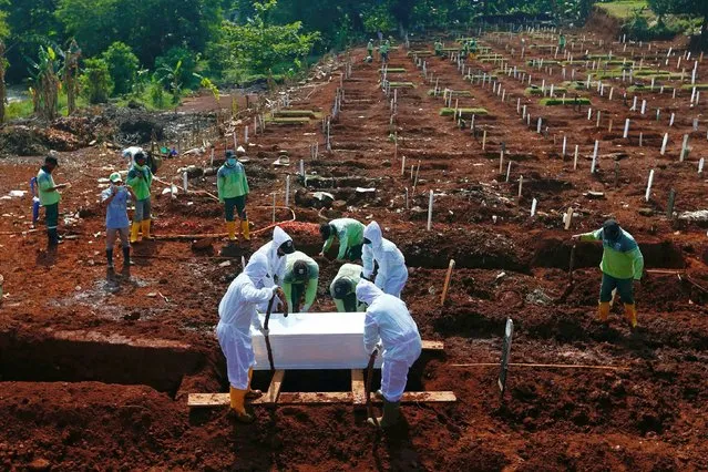 Workers wearing protective suits bury a coffin at the Muslim burial area provided by the government for victims of the coronavirus disease (COVID-19) at Pondok Ranggon cemetery complex in Jakarta, Indonesia, September 16, 2020. (Photo by Ajeng Dinar Ulfiana/Reuters)