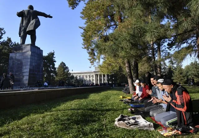 Protesters pray as they wait for Kyrgyz Prime Minister Sadyr Zhaparov speech in front of the government building with a statue of Vladimir Lenin on the left, in Bishkek, Kyrgyzstan, Wednesday, October 14, 2020. Kyrgyzstan's embattled president has discussed his possible resignation with his newly appointed prime minister in a bid to end the political crisis in the Central Asian country after a disputed parliamentary election. President Sooronbai Jeenbekov held talks with Prime Minister Sadyr Zhaparov a day after refusing to appoint him to the post over concerns whether parliament could legitimately nominate him. (Photo by Vladimir Voronin/AP Photo)