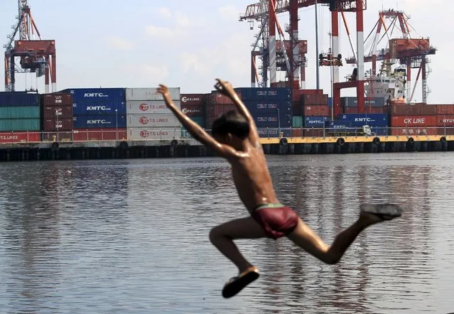 Stacks of containers are seen while a boy dives on a river near a port in the capital Manila October 9, 2015. (Photo by Romeo Ranoco/Reuters)