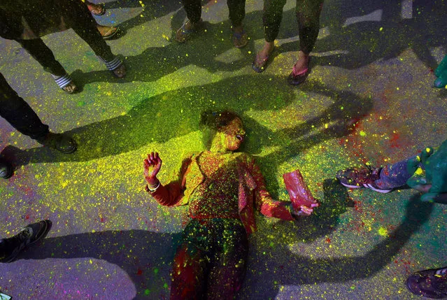 A student reacts as she lies in a road while coloured powder is thrown on her during Holi celebrations outside her college hostel in Chandigarh, India on March 2, 2018. (Photo by Ajay Verma/Reuters)