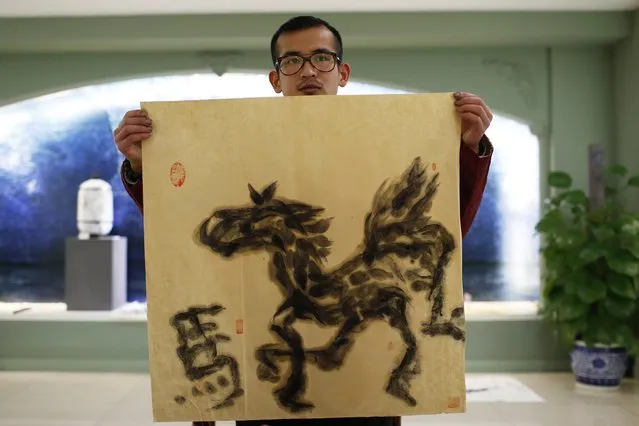 Folk artist Han Xiaoming shows his completed artwork of a horse painted entirely with his tongue in Hangzhou, Zhejiang province December 4, 2014. (Photo by Aly Song/Reuters)