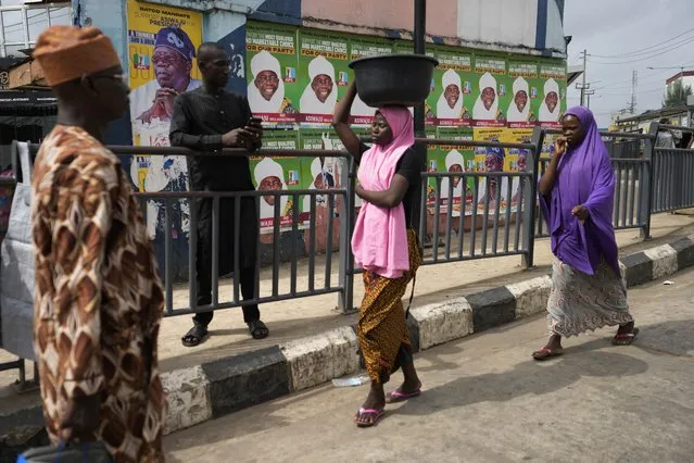 People walk past posters of Presidential candidate Bola Tinubu of the All Progressives Congress in Lagos, Nigeria Monday, February 27, 2023. Each of the three frontrunners in Nigeria's hotly contested presidential election claimed they were on the path to victory Monday, as preliminary results trickled in two days after Africa's most populous nation went to the polls. (Photo by Sunday Alamba/AP Photo)