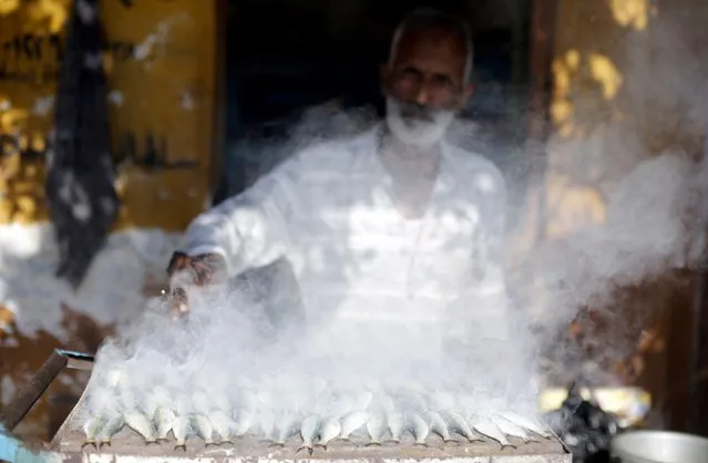 A man grills fish to sell, in front of his house in the fishermen's village in El Max in the Mediterranean city of Alexandria October 18, 2014. (Photo by Amr Abdallah Dalsh/Reuters)