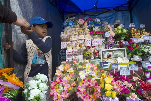 A girl collects payment at a shop outside a cemetery known for its topiary art, during the observance of the Day of the Dead, in Tulcan, Ecuador November 2, 2015. (Photo by Guillermo Granja/Reuters)