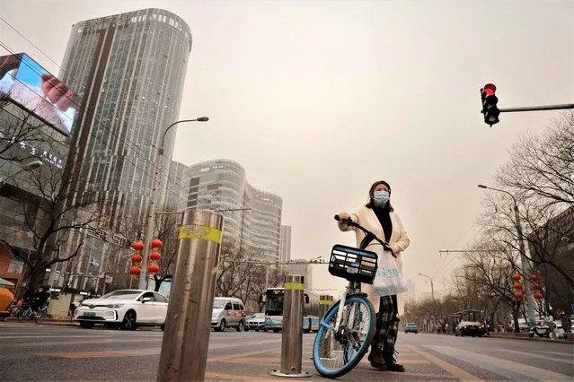 A cyclist waits to cross a street on a polluted day in Beijing, China on March 10, 2023. (Photo by Thomas Peter/Reuters)