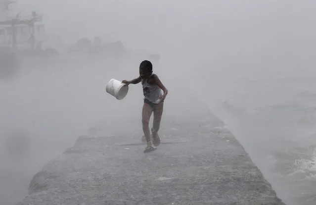 A boy runs as heavy rains and high waves brought by typhoon Linfa, locally named Egay, crash along a breakwater along Manila Bay at a slum area in Baseco, Tondo in Manila, July 6, 2015. (Photo by Romeo Ranoco/Reuters)