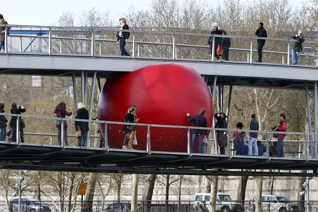 A huge red ball is installed on the Simone de Beauvoir's bridge as part of the RedBall Project by artist Kurt Perschke in Paris April 20, 2013. The RedBall Project is touring Paris from April 18 to 28, changing its location each day. (Photo by Charles Platiau/Reuters)