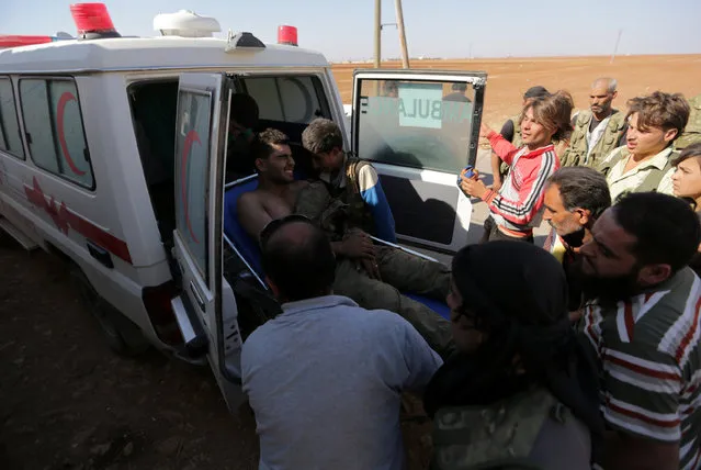 Rebel fighters move an injured fellow member into an ambulance, after bringing him from the Guzhe frontline, near Guzhe village, northern Aleppo countryside, Syria October 17, 2016. (Photo by Khalil Ashawi/Reuters)