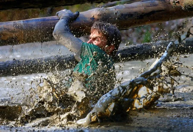 A competitor crosses a water obstacle during the Wildsau Dirt Run (Wild Boar Dirt Run) obstacle course fun race at Hellsklamm ravine in Obertriesting, Austria, October 22, 2016. (Photo by Heinz-Peter Bader/Reuters)