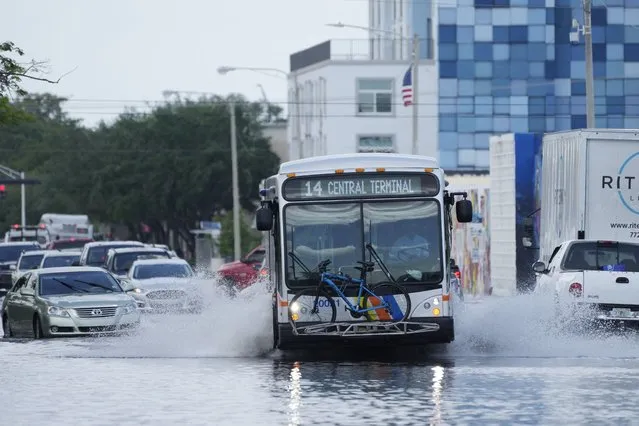A city bus makes its way through receding floodwaters on Avenue of the Arts in Fort Lauderdale, Fla., Thursday, April 13, 2023. Over 25 inches of rain fell in South Florida since Monday, causing widespread flooding. (Photo by Rebecca Blackwell/AP Photo)