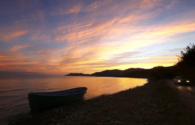 A local farmer drives his pick-up truck as a wooden boat, used by migrants and refugees, is abandoned at a beach at dawn on the Greek island of Lesbos November 16, 2015. (Photo by Yannis Behrakis/Reuters)