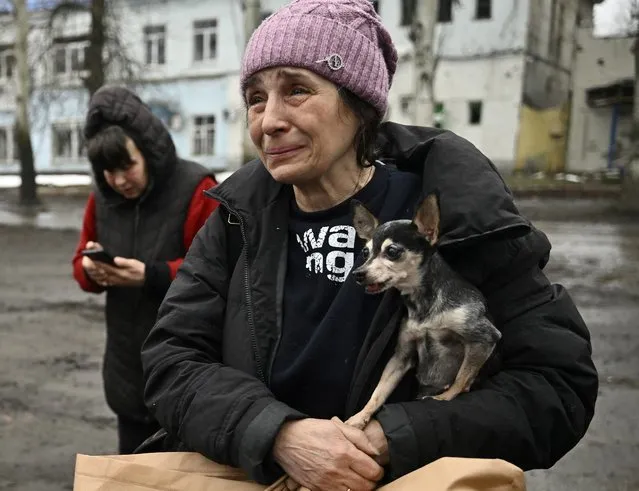 Lyuba  civilian evacuated from Bakhmut cries while carrying her shivering chihuahua, Margot after steping out of a Ukrainian army armored personnel carrier (APC) in Chasiv Yar on April 3, 2023, amid the Russian invasion of Ukraine. (Photo by Genya Savilov/AFP Photo)