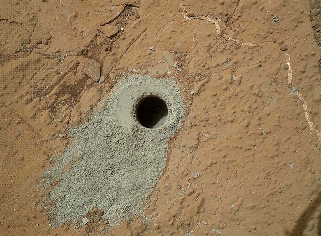This image released by NASA shows a hole in a Martian rock drilled by the NASA rover Curiosity on May 19, 2013. It's the second drilling by the spacecraft since landing in August 2012. Curiosity used the Mars Hand Lens Imager camera on the rover's arm to capture this view of the hole in the rock, dubbed “Cumberland”.  The diameter of the hole is about 0.6 inch and the depth about 2.6 inches. In the coming days, Curiosity will transfer the rock powder to its onboard instruments to analyze the chemical makeup. (Photo by NASA/JPL-Caltech/MSSS)