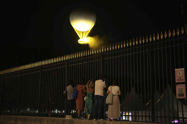People watch the cauldron with the Paralympic flame rise at the end of the Opening Ceremony for the 2024 Paralympics, Wednesday, August 28, 2024, in Paris, France. (Photo by Emilio Morenatti/AP Photo)
