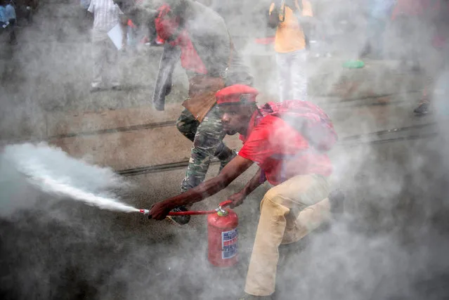 An EFF supporter sprays a fire extinguisher as members and supporters of the South African opposition party, the Economic Freedom Fighters (EFF), demonstrate against South Africa's president Jacob Zuma and in support of the release of the South African Public Protector “State Capture” report in Pretoria on November 2, 2016. South Africa's anti-corruption watchdog November 2 called for prosecutors to investigate alleged criminal activity as it released a report into President Jacob Zuma that fuelled further calls for him to resign. Zuma, whose presidency has been engulfed by multiple scandals, had fought to block the release of the Public Protector's report, but his lawyers made a surprise U-turn and dropped their legal appeal. The report was released hours later, further undermining Zuma after a series of court rulings that have tarnished his time in office and the ruling ANC party that led the fight to end apartheid rule. (Photo by Mujahid Safodien/AFP Photo)