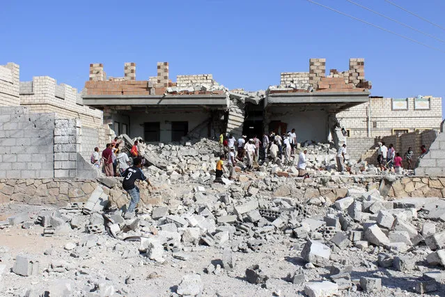 People gather outside a house destroyed by an air strike on a suspected hideout of al Qaeda militants in al-Shiher city of Yemen's southeastern province of Hadramount November 22, 2013. (Photo by Reuters/Stringer)