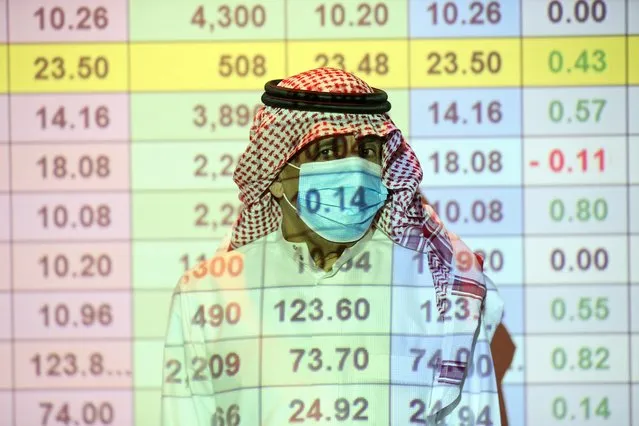 A Saudi trader wears a mask as he monitors stock information at the Saudi stock market in Riyadh, Saudi Arabia on August 25, 2020. (Photo by Ahmed Yosri/Reuters)