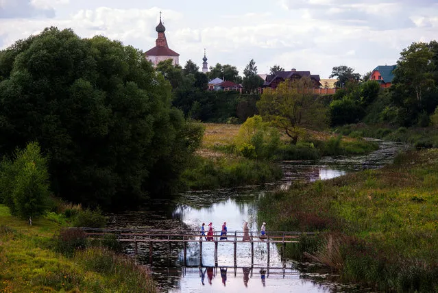 People cross the river on a wooden bridge on August 4, 2015 in Suzdal, a tourist spot being part of ancient Russia cities, known as the “Golden Ring”. (Photo by Alexander Utkin/AFP Photo)