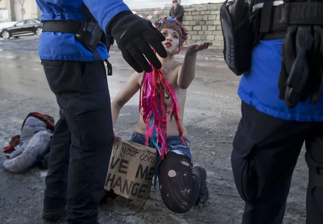 A FEMEN activist, who is protesting against the financial world, discusses with police at the World Economic Forum in Davos, Switzerland, Thursday, January 22, 2015. The meeting runs from Jan. 21 through Jan. 24. (Photo by Michel Euler/AP Photo)