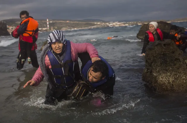 Refugees from Afghanistan make their way out of the sea, as their boat, on which they crossed a part of the Aegean sea from Turkey, hit on rocks on the Greek island of Lesbos, on Saturday, December 12, 2015. Any link between extremism and the thousands of people fleeing violence in Syria and elsewhere is false, a top European human rights official said Friday, noting that those who have perpetrated recent attacks in Europe were citizens of European countries. (Photo by Santi Palacios/AP Photo)
