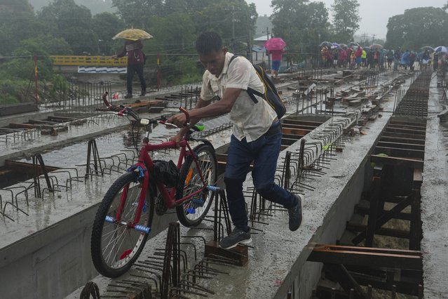 Residents cross a bridge under construction amid rain showers brought on by Tropical Storm Sara, on the outskirts of San Pedro Sula, Honduras, Saturday, November 16, 2024. (Photo by Moises Castillo/AP Photo)