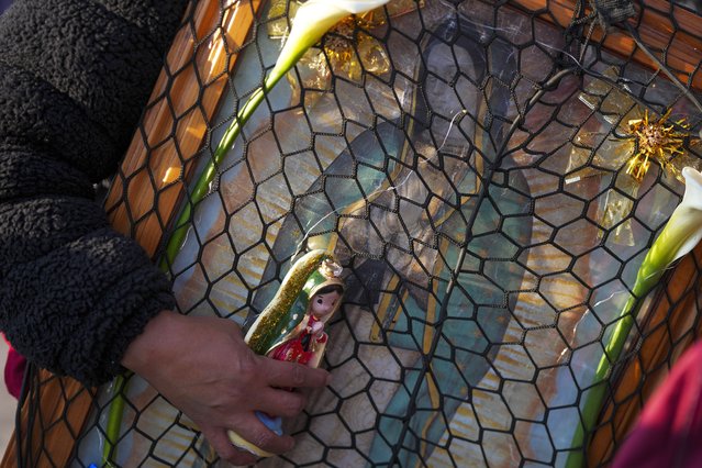 A pilgrim holds religious icons representing Our Lady of Guadalupe during one of the world's largest religious pilgrimages to Our Lady of Guadalupe Basilica, marking the feast day of the patroness of Latin America in Mexico City, Thursday, December 12, 2024. (Photo by Fernando Llano/AP Photo)