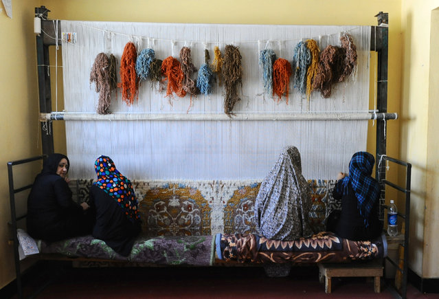 In this photograph taken on August 27, 2014 female Afghan prisoners weave a carpet in the female prison in Herat. The facility, which was built by the Italian Provincial Reconstruction Team, holds approximately 140 inmates, some with their children alongside them, whose crimes range from murder, drug trafficking to running away from home.  The prison programme includes teaching inmates skills, such as carpet weaving, that will help them survive when they are released. (Photo by Aref Karimi/AFP Photo)