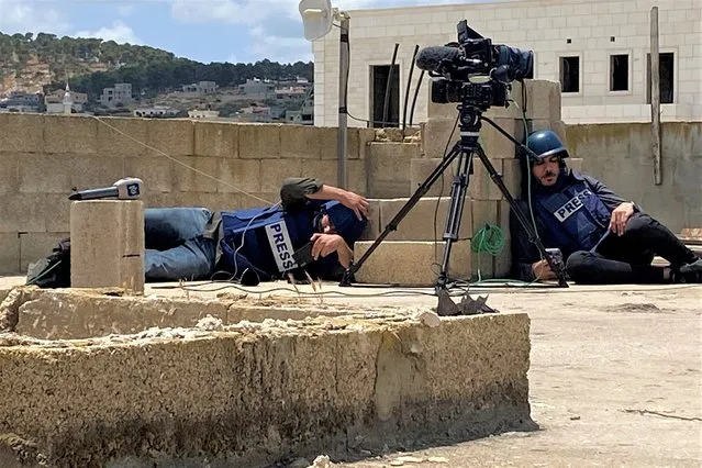 Palestinian journalists take cover while caught under fire on a rooftop while covering an Israeli raid in Jenin, in the Israeli-occupied West Bank on June 19, 2023. (Photo by Ashraf Shaweesh/Reuters)