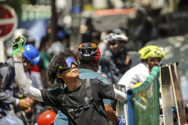A protester prepares to throw a part of banana towards the police during a protest against the military coup in Yangon, Myanmar, Tuesday, March 2, 2021. (Photo by AP Photo/Stringer)