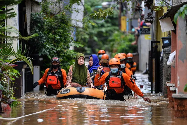 Volunteers evacuate elderly women with an inflatable boat in an area affected by floods, following heavy rains in Jakarta, Indonesia, February 19, 2021. (Photo by Sigid Kurniawan/Antara Foto via Reuters)