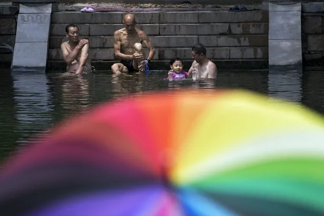 Residents cool off from a hot day at an urban waterway in Beijing, Monday, July 3, 2023. (Photo by Andy Wong/AP Photo)